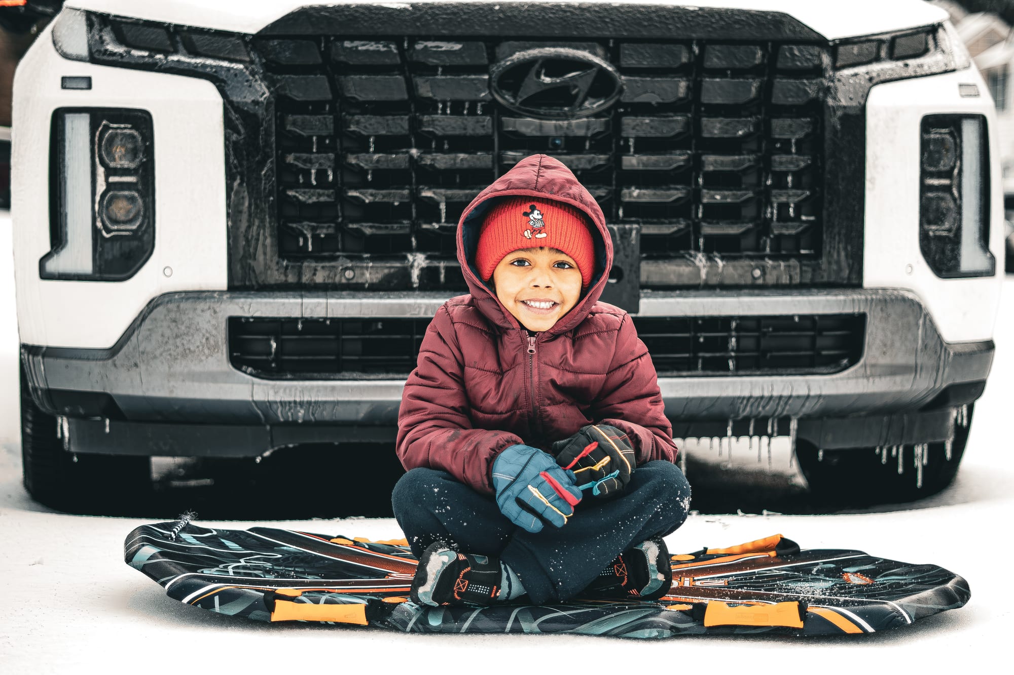 A little boy bundled up in a winter jacket and hat